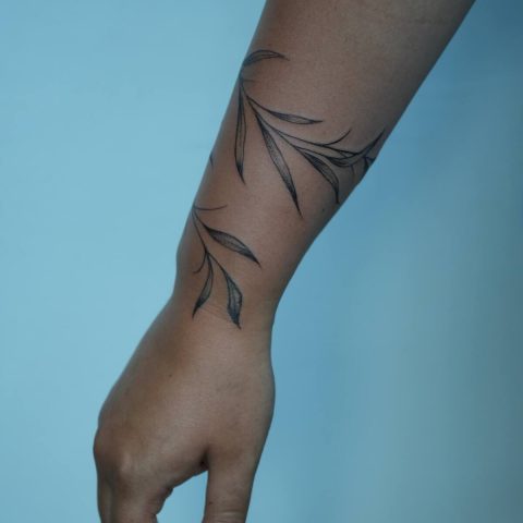 Fine line vine tattoo running down an arm